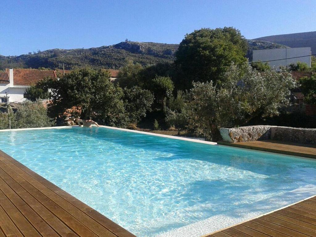 a large blue swimming pool with a mountain in the background at Casa dos Aromas - Nature Tourism in Alvados