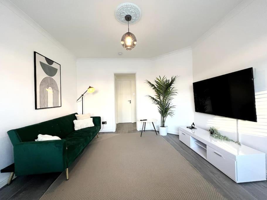 een woonkamer met een groene bank en een flatscreen-tv bij ArtLounge-2 bed garden Free parking in Enfield Lock