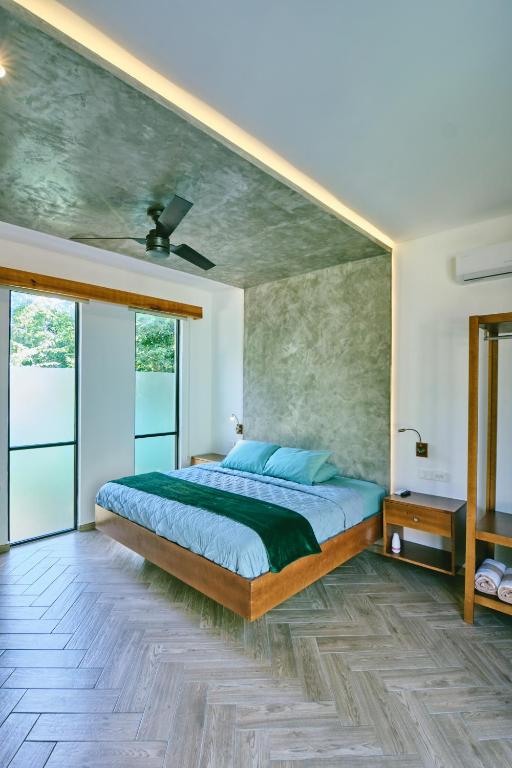 a bedroom with a large bed and glass doors at Villas Zamna - Jungle Villas in Cozumel