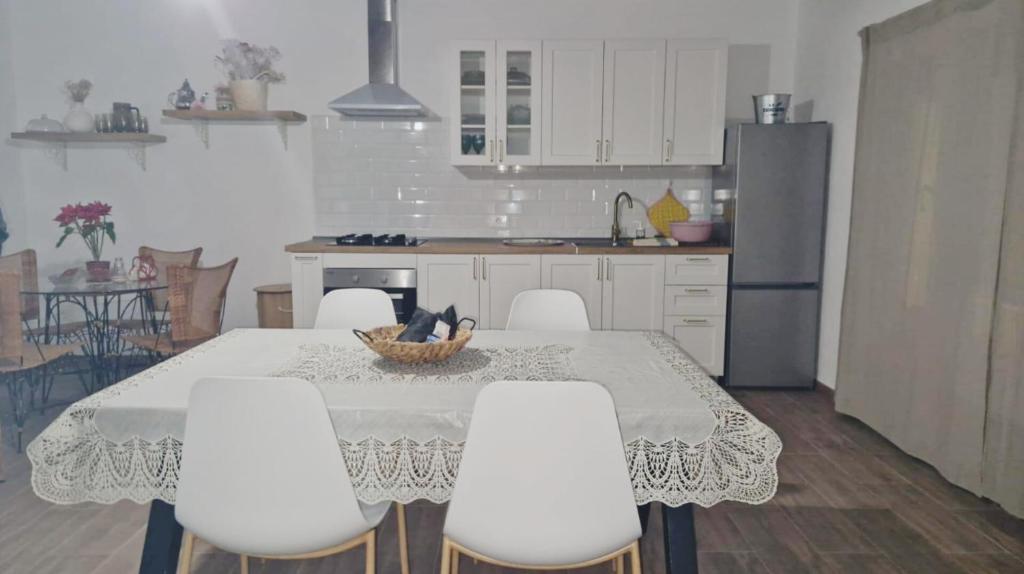 cocina con mesa, sillas blancas y nevera en Apartamento Casa Rosabella, en Caleta de Sebo