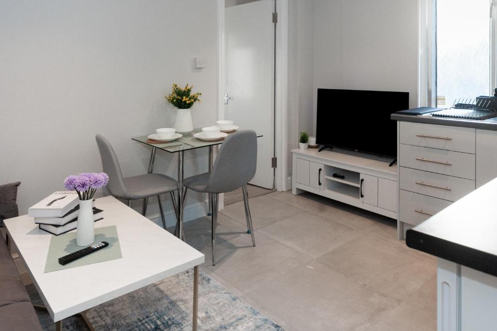 ein Wohnzimmer mit einem Tisch und einem TV in der Unterkunft Chic 1BR Gem, Croydon Central in Croydon