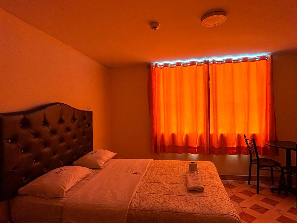 1 dormitorio con 1 cama con cortina naranja en Hospedaje San Blas en Lima