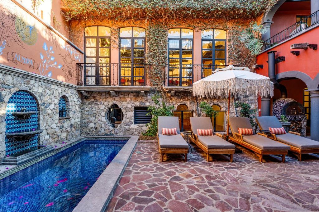 a pool with chairs and an umbrella next to a building at Casa Almira 5BR Luxury Home with Pool, Hot Tub & Rooftop in San Miguel de Allende