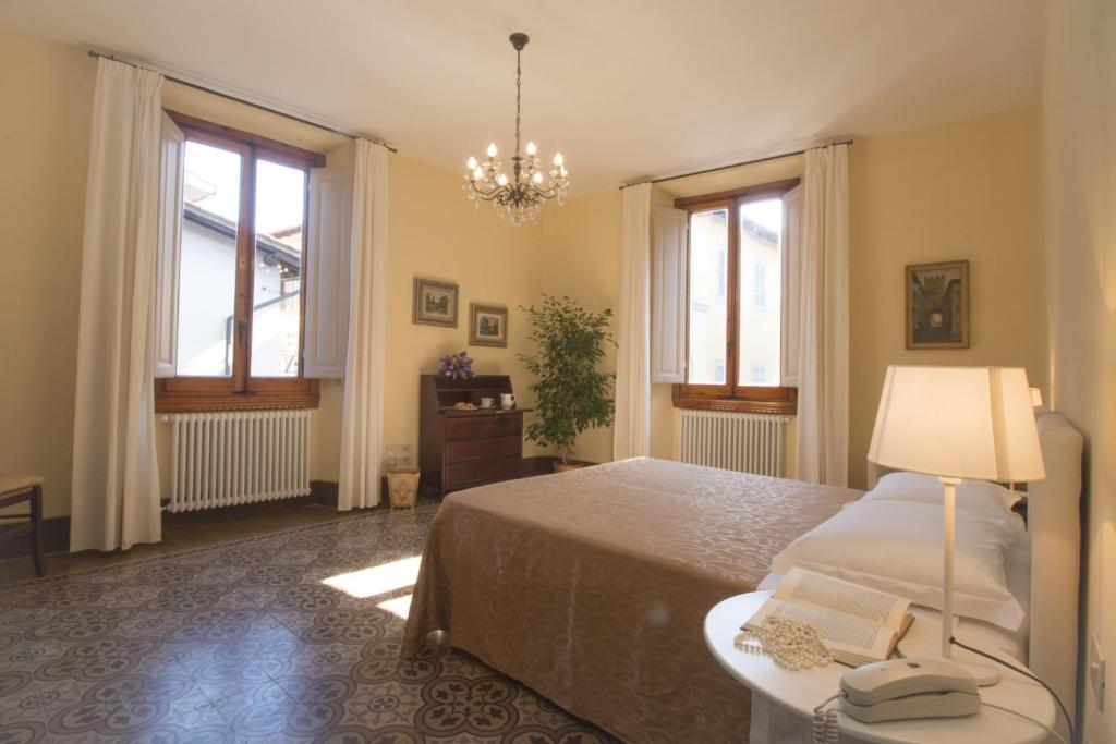 a bedroom with a bed and a lamp and two windows at Dimora Pieri in Florence