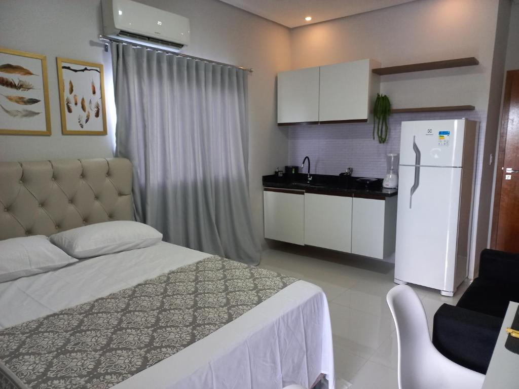 a bedroom with a bed and a kitchen with a refrigerator at apartamento studio setor Sul in Palmas