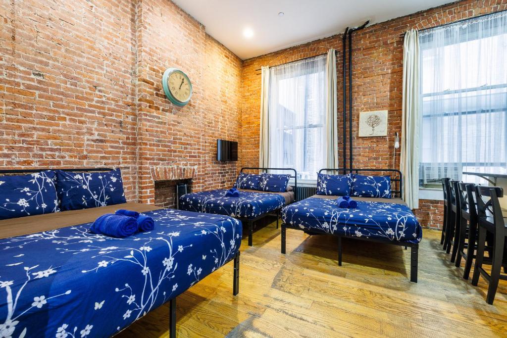 Habitación con camas y sillas azules y pared de ladrillo. en Studios in New York en Nueva York