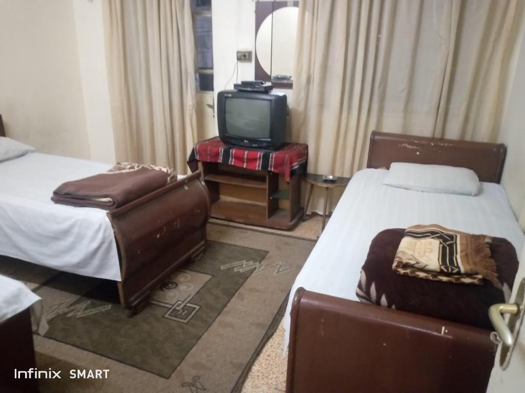 a hotel room with two beds and a tv at Al Amawi Hostel in Amman