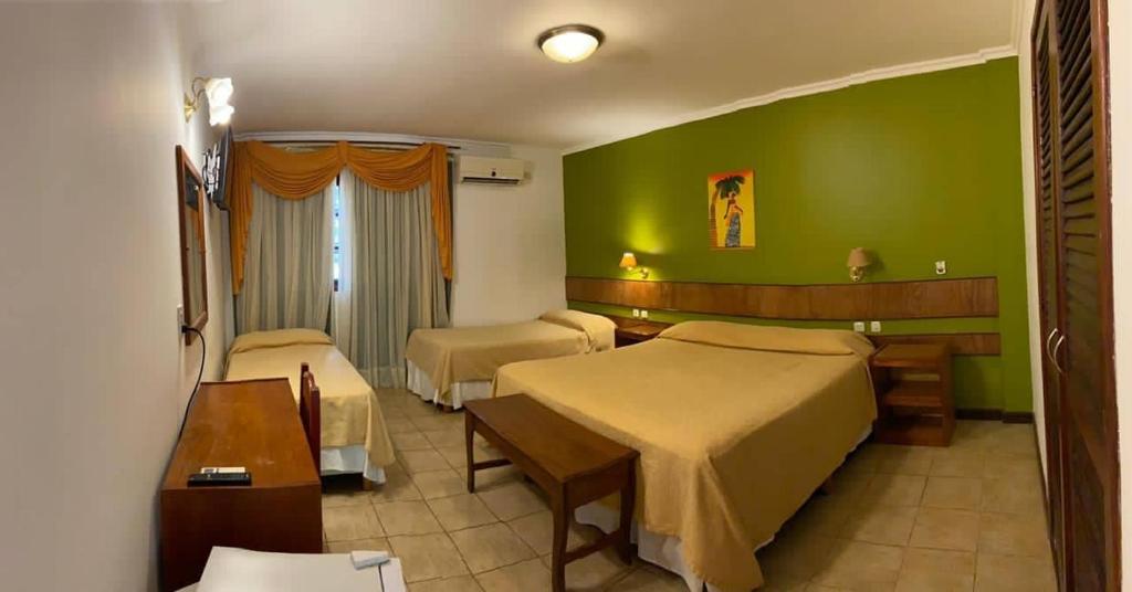 Habitación de hotel con 2 camas y paredes verdes en Hotel Cabañas del Leñador en Puerto Iguazú