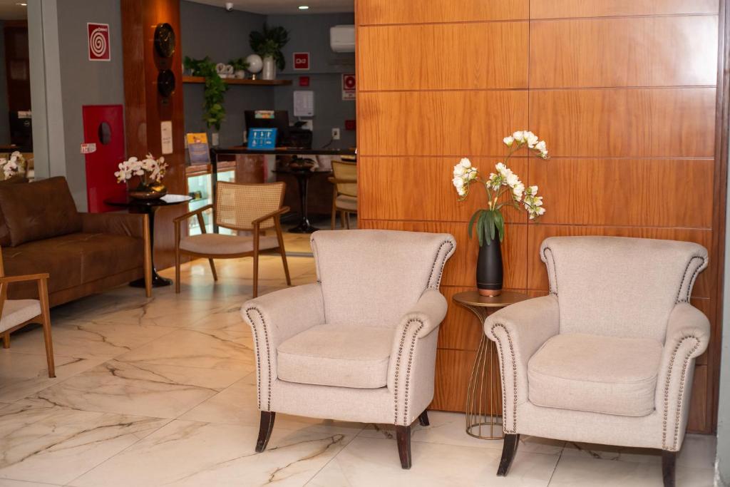 - un hall avec deux chaises et une table avec un vase de fleurs dans l'établissement Nobile Hotel Juiz de Fora, à Juiz de Fora