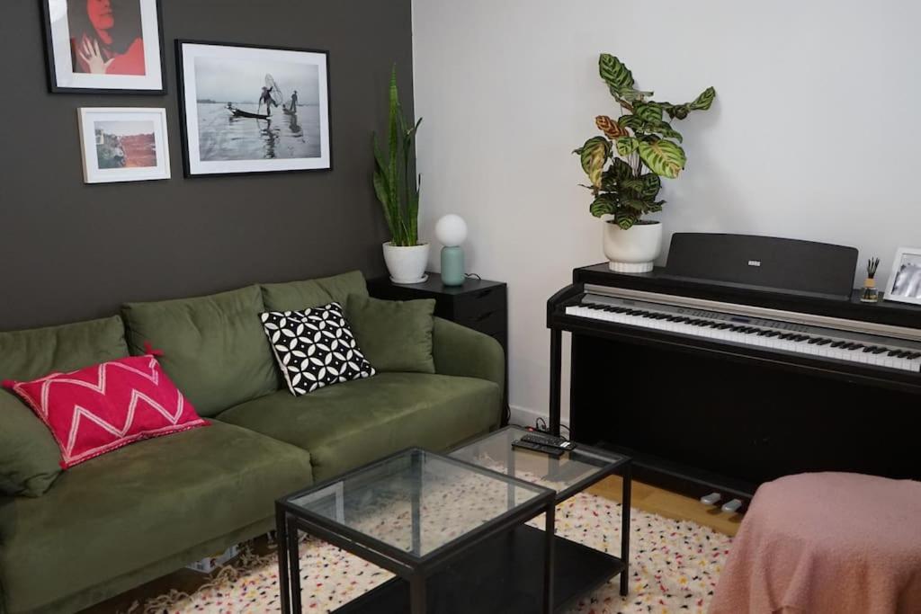 een woonkamer met een groene bank en een piano bij Appartement au cœur du Marais in Parijs