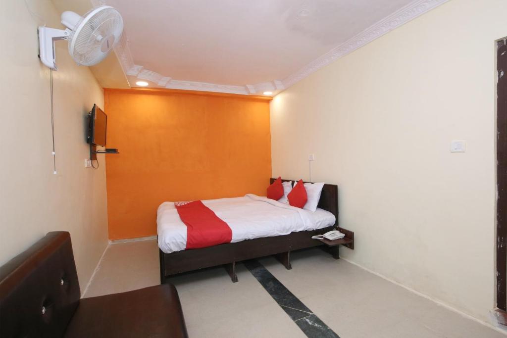 een kleine slaapkamer met een bed met rode en witte kussens bij OYO Hotel Vn Residency in Jabalpur