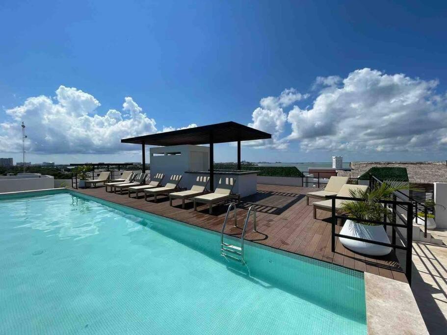 a swimming pool with chairs and a gazebo on a building at New apartment Neen in Cancún