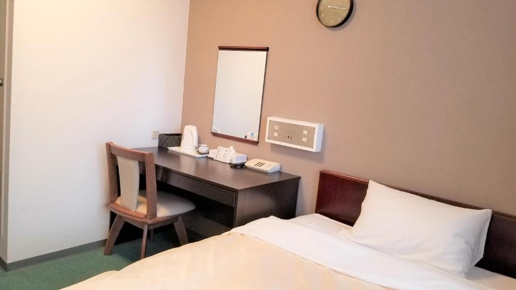 a bedroom with a desk with a bed and a mirror at Hotel Crown Hills Imabari in Imabari
