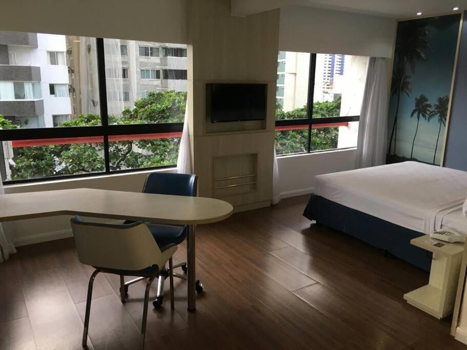 une chambre d'hôtel avec un lit, une table et des chaises dans l'établissement Flat no Mercure Navegantes, à Récife