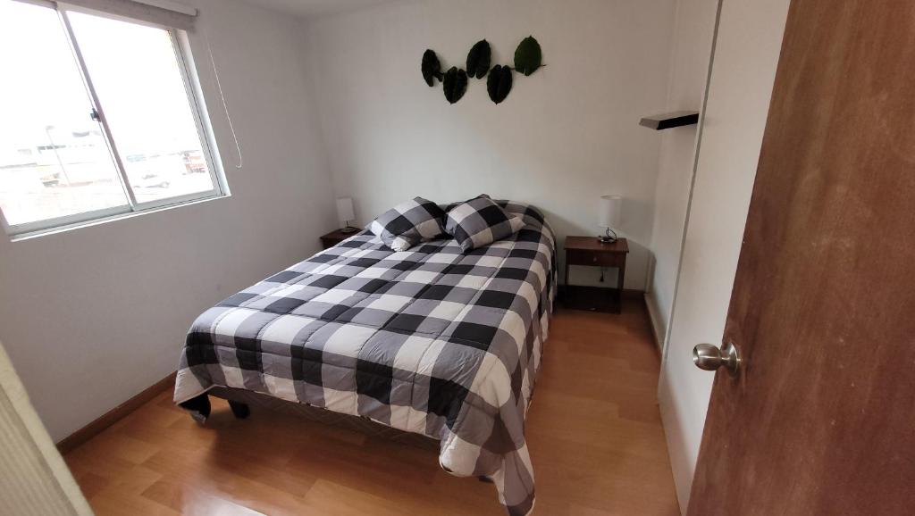 1 dormitorio con cama a cuadros en blanco y negro en departamentos Iquique cercano al Mall Plaza en Iquique