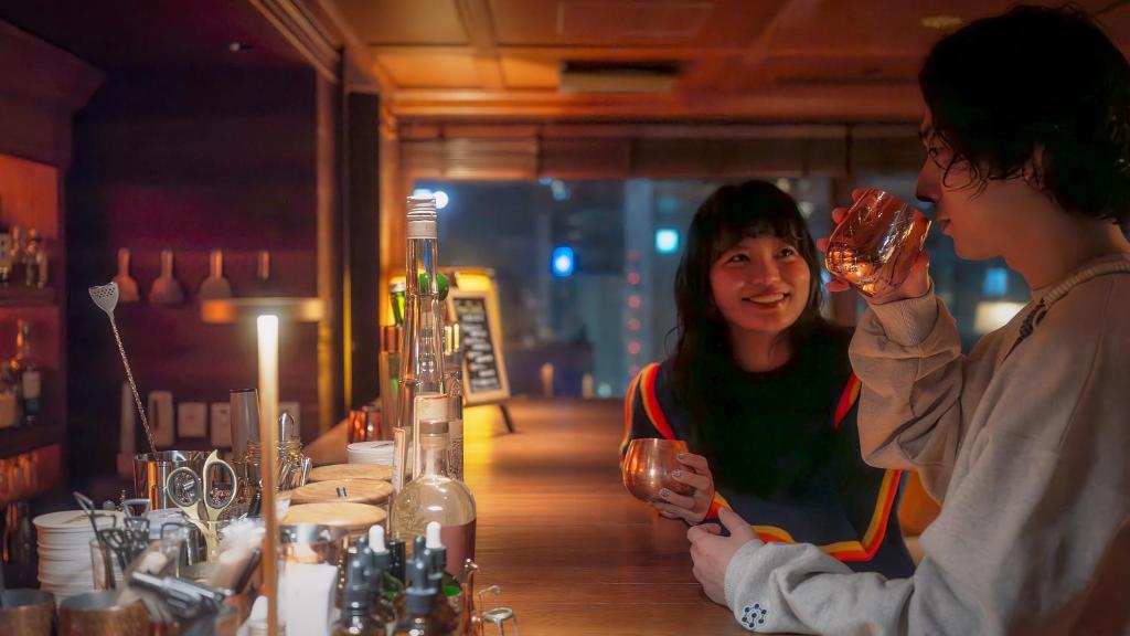 two people standing at a bar drinking wine at UNWIND Hotel & Bar 札幌 in Sapporo