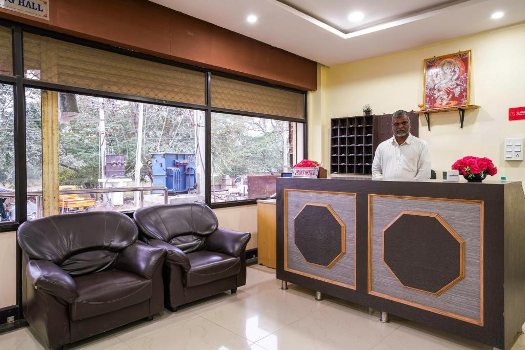 a man standing at a bar in a waiting room at 69076 OYO Hotel Sweekar in Shamshabad