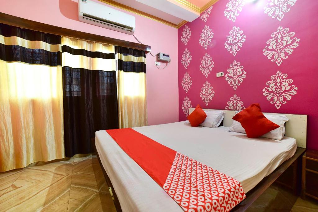 a bedroom with pink walls and a bed with red pillows at OYO Flagship Ashoka Guest House in Bihta