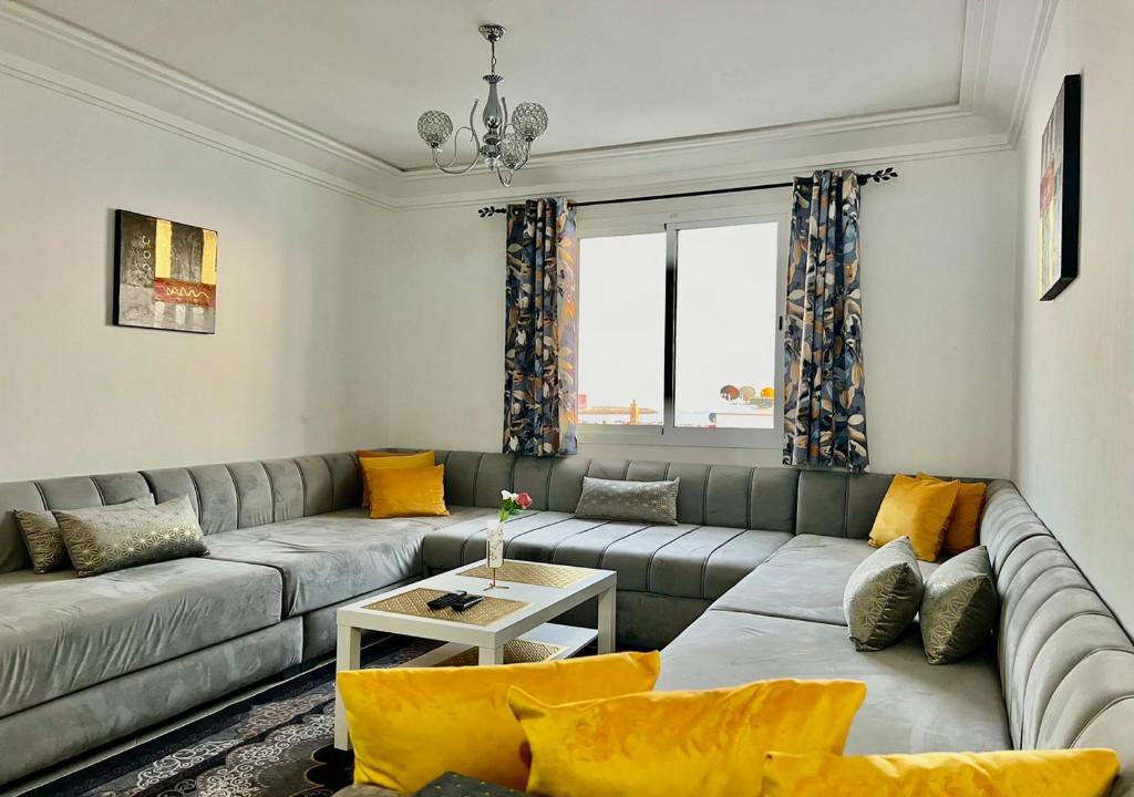 Bord de Mer: Appartement à 500m de la Plage & Surf في أغادير: غرفة معيشة مع أريكة رمادية ووسائد صفراء