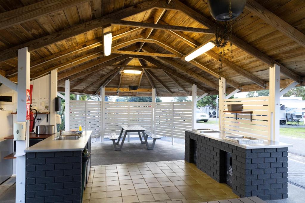 eine Außenküche mit einem Tisch und einem Tisch in der Unterkunft Reflections Forster Beach - Holiday Park in Forster