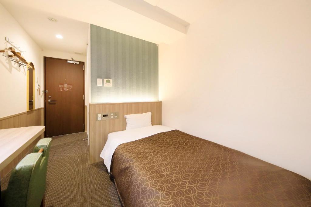 a hotel room with a bed and a door at Hotel Shinjukuya in Machida