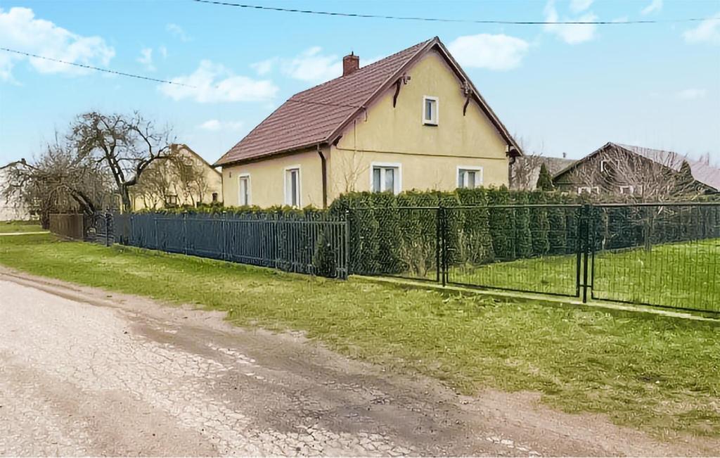 a house with a fence in front of a yard at Stunning Home In Trynisze Moszewo With Wifi in Ciechanowiec
