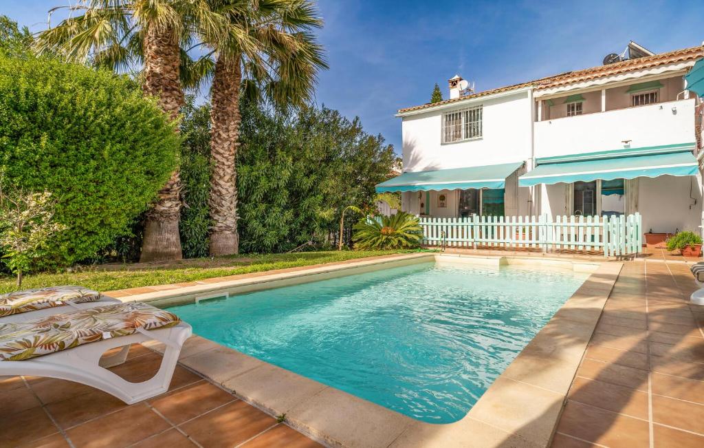 una piscina frente a una casa con palmeras en Gorgeous Home In Las Lagunas De Mijas With Kitchen, en Santa Fe de los Boliches