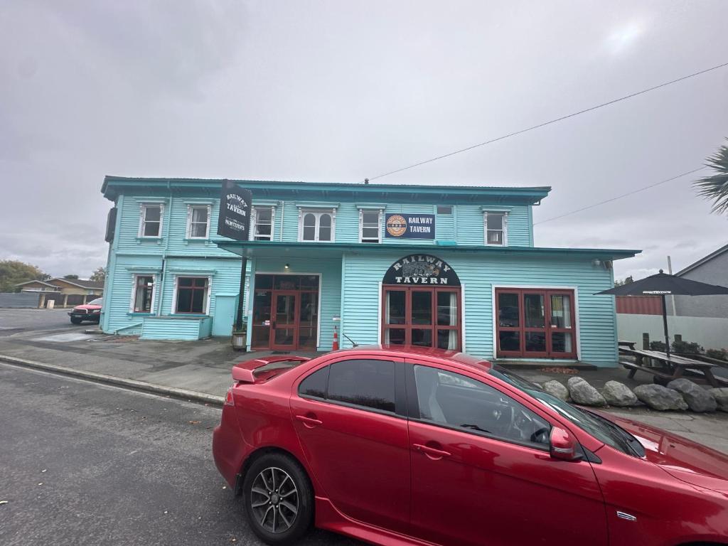 a red car parked in front of a blue building at Railway Hotel in South Rakaia