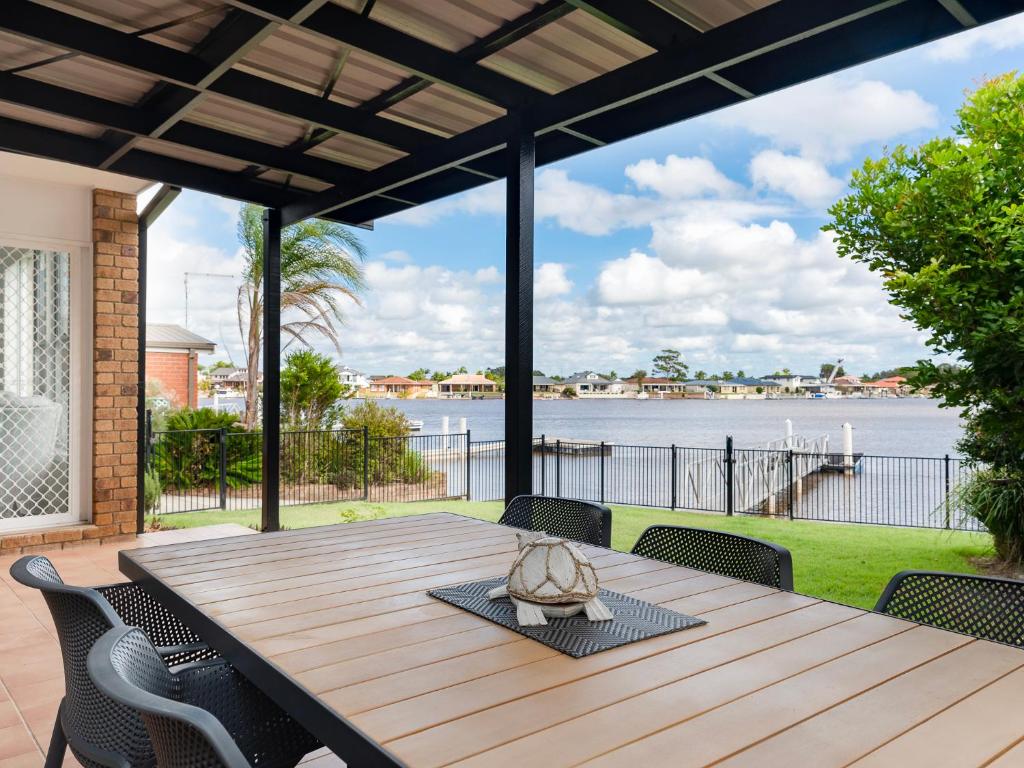a wooden table with chairs and a view of the water at 21 Melaleuca Drive -LJHooker Yamba in Yamba
