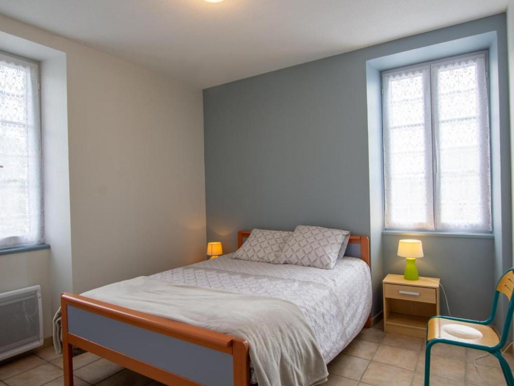 a bedroom with a bed and a chair and two windows at Appartement Saint-Mesmin, 3 pièces, 5 personnes - FR-1-616-213 in Saint-Mesmin
