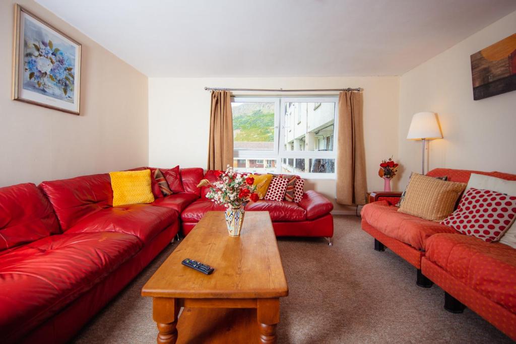 a living room with a red couch and a table at Fab Arthur Seat Views, Old Town Apartment in Edinburgh