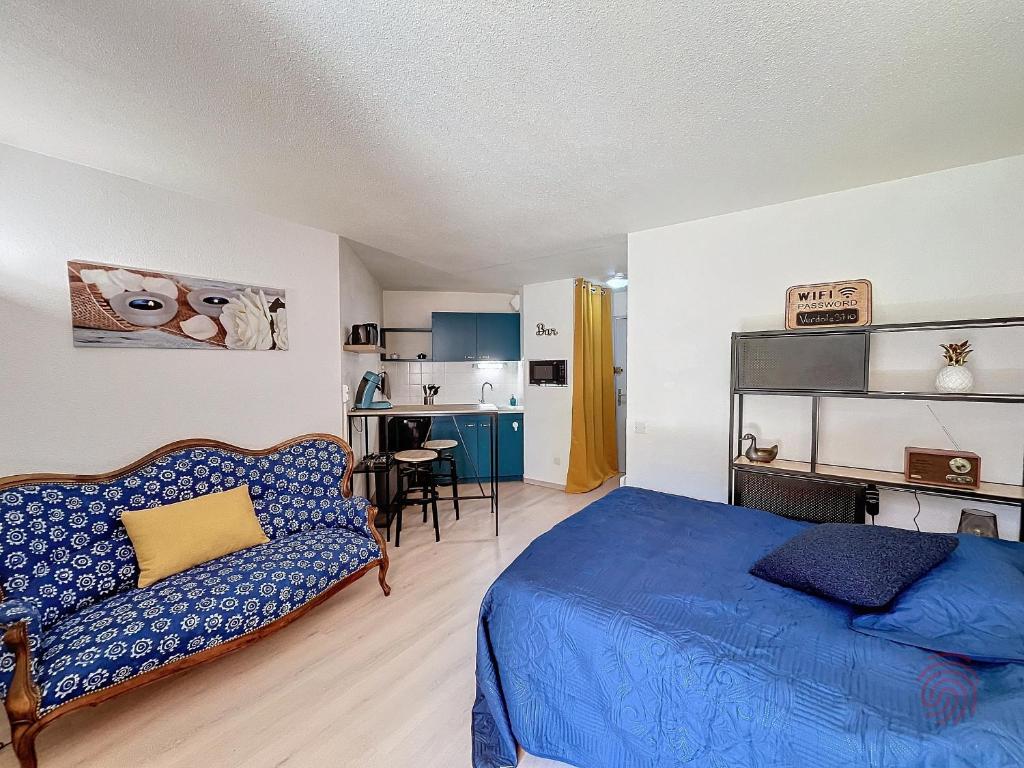 ein Schlafzimmer mit einem blauen Bett und einem Sofa in der Unterkunft Studio Lamalou-les-Bains, 1 pièce, 2 personnes - FR-1-451-207 in Lamalou-les-Bains