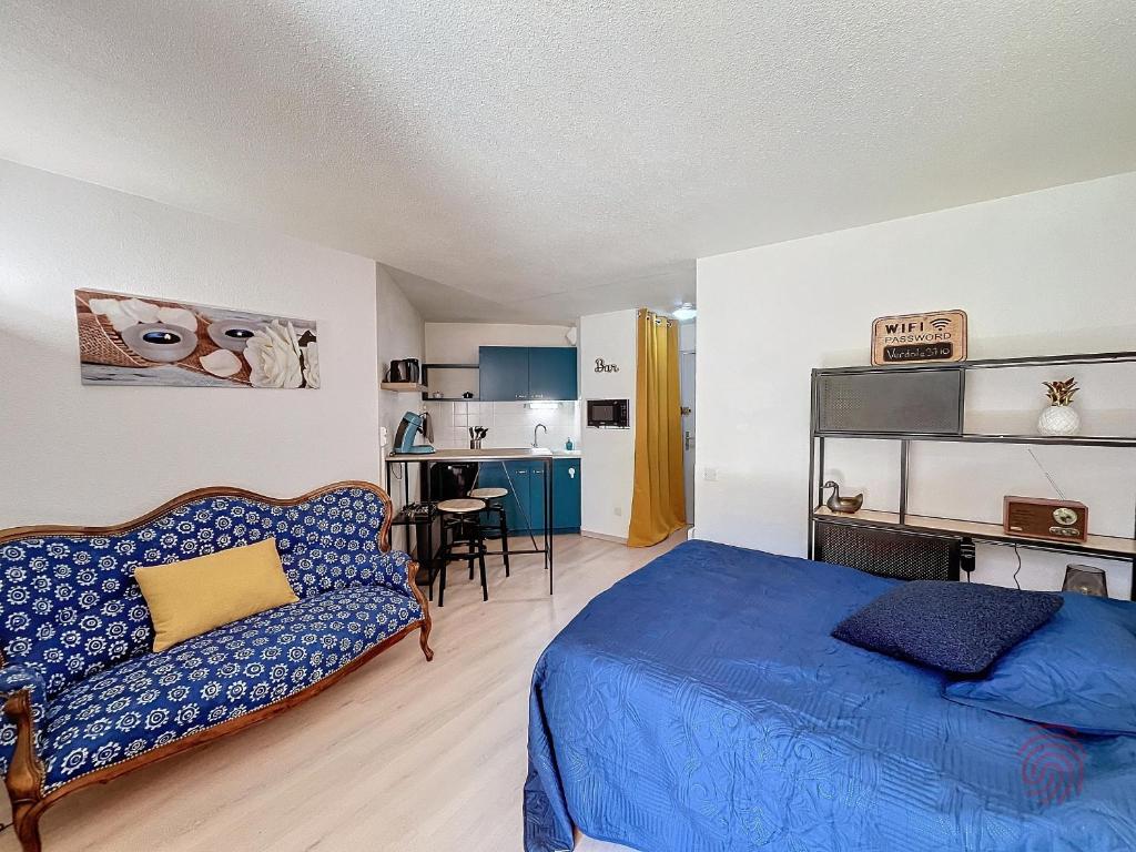 - une chambre avec un lit bleu et un canapé dans l'établissement Charmant Studio RDC à Lamalou, Terrasse, Proche Thermes, Wifi, Animaux OK - FR-1-451-207, à Lamalou-les-Bains