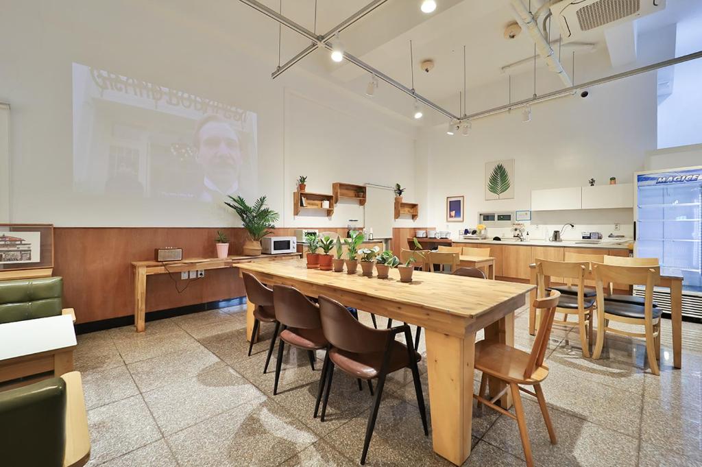 慶州市にあるCiel mini hotelの大きな木製テーブルと椅子が備わる広い客室です。