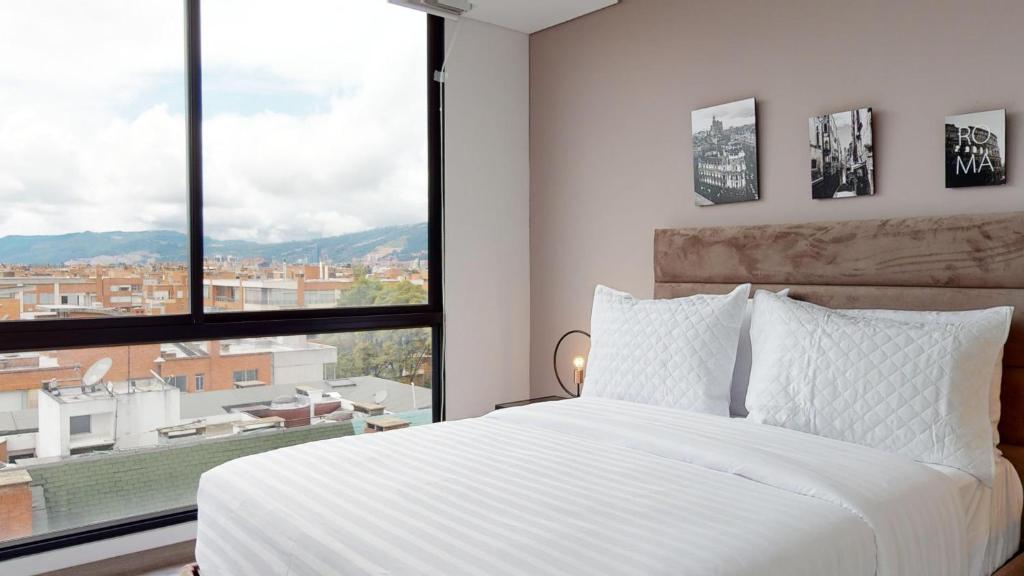 een slaapkamer met een wit bed en een groot raam bij Your Central Base near Unicentro in Bogota