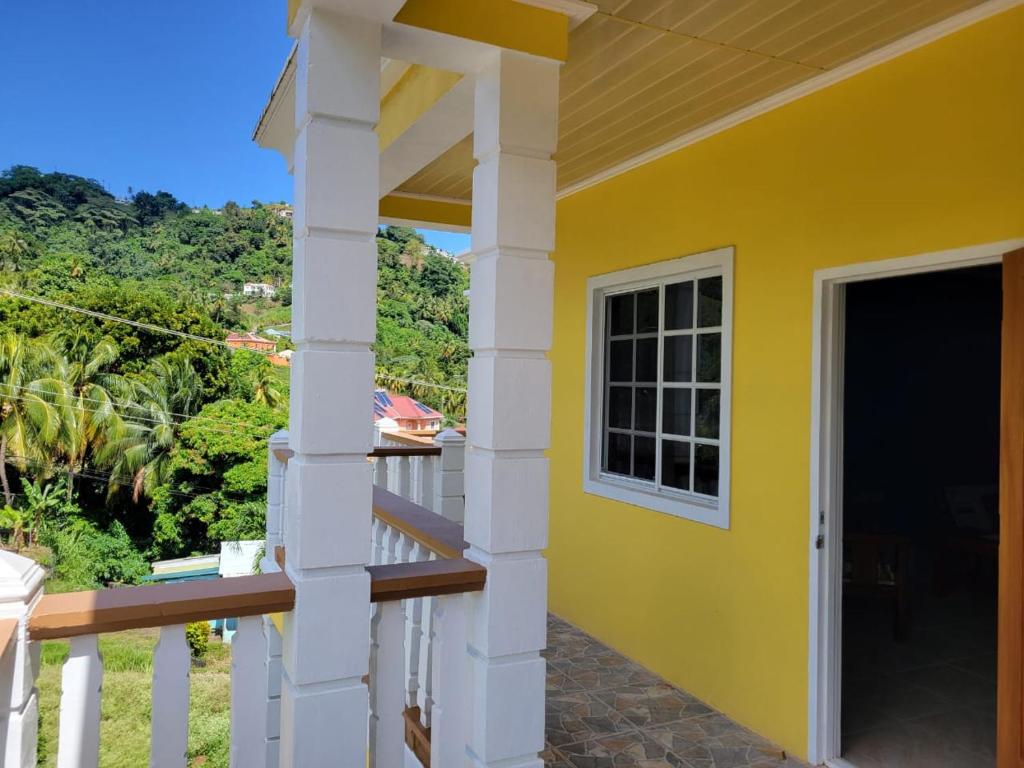 ein gelbes Haus mit einem Balkon mit Tür in der Unterkunft Spring View Apartment in Belmont