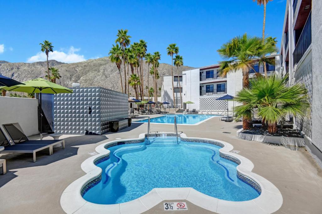 una piscina con palme e un edificio di The Dunes Hotel (Palm Springs) a Palm Springs