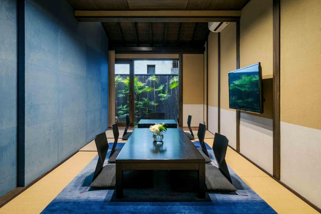 a dining room with a table and chairs and a television at Asagi an Machiya House in Kyoto