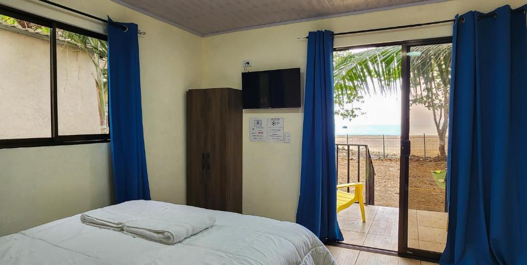 a bedroom with a bed and a view of the beach at Pura Vida Macaw Paradise in Jacó