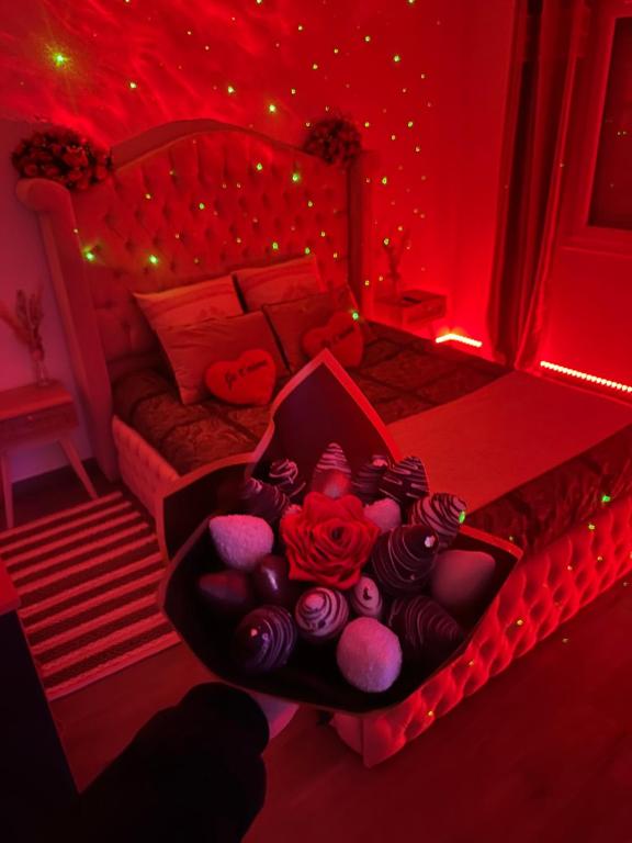ein rotes Schlafzimmer mit einem Bett mit einer Schachtel Rosen in der Unterkunft Deluxe appartement Jacuzzi in Freneuse