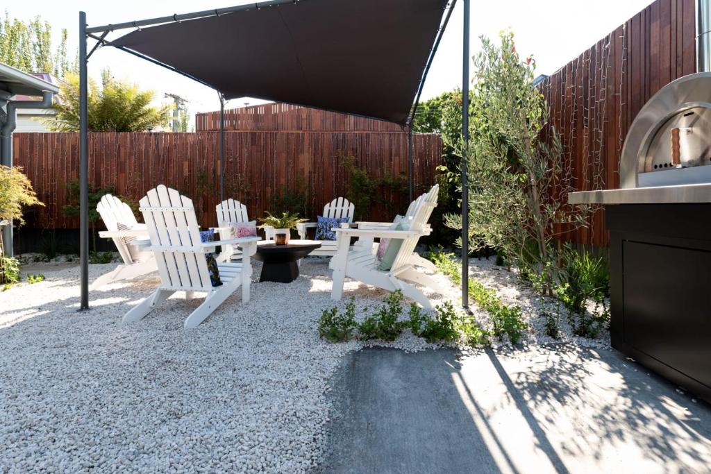 eine Terrasse mit weißen Stühlen, einem Tisch und einem Sonnenschirm in der Unterkunft Bluebell Cottage in Invermay