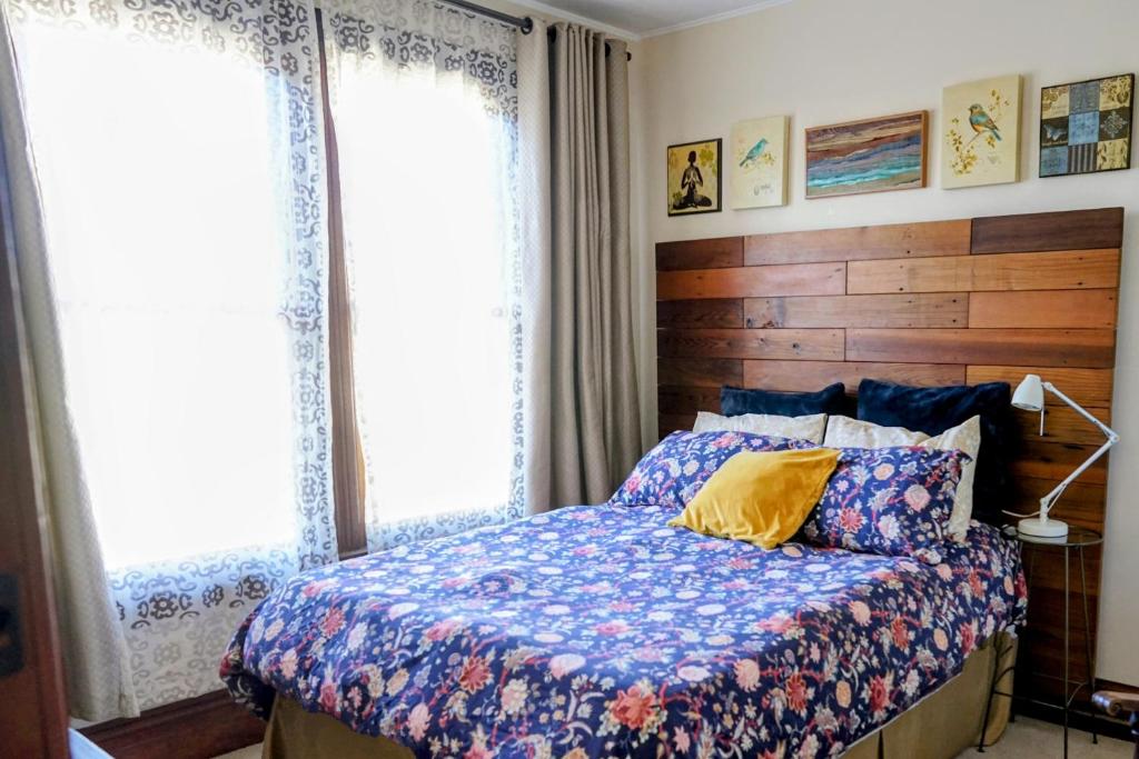 a bedroom with a bed with a wooden headboard and two windows at Perfect Location - 4BD,1BA - Restored Redwood Home in San Francisco
