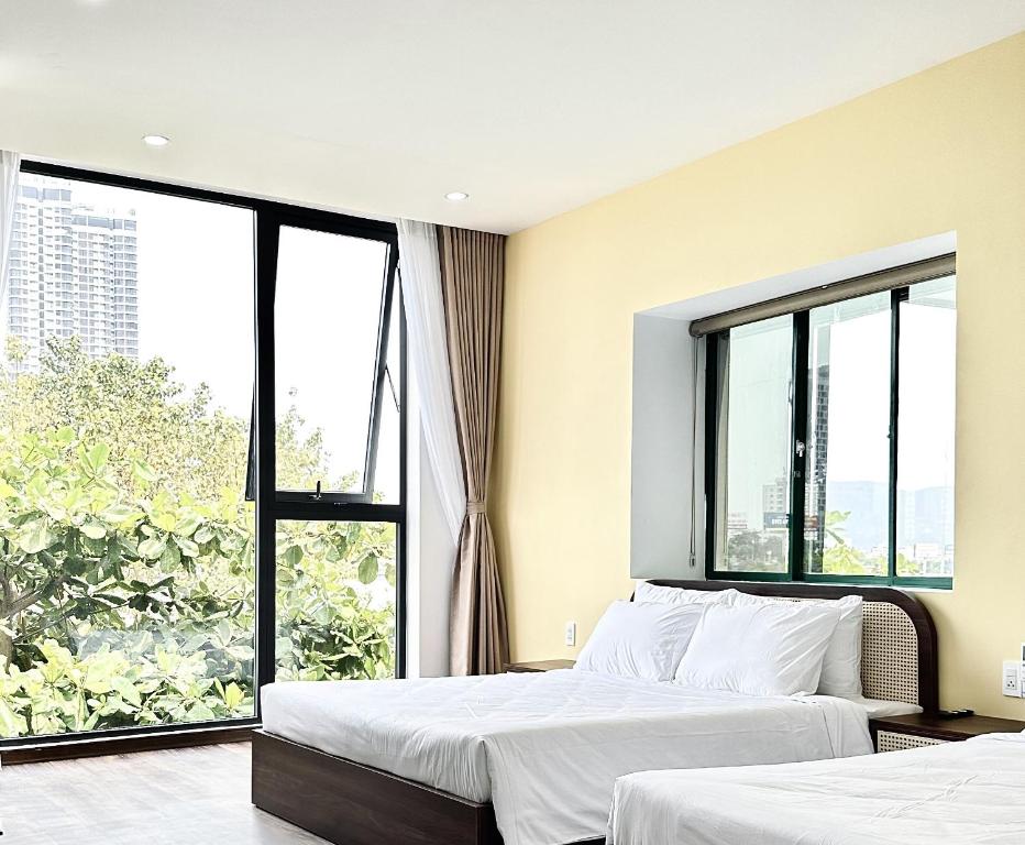 two beds in a room with large windows at Han Riverine Hotel & Cafeteria DaNang in Danang