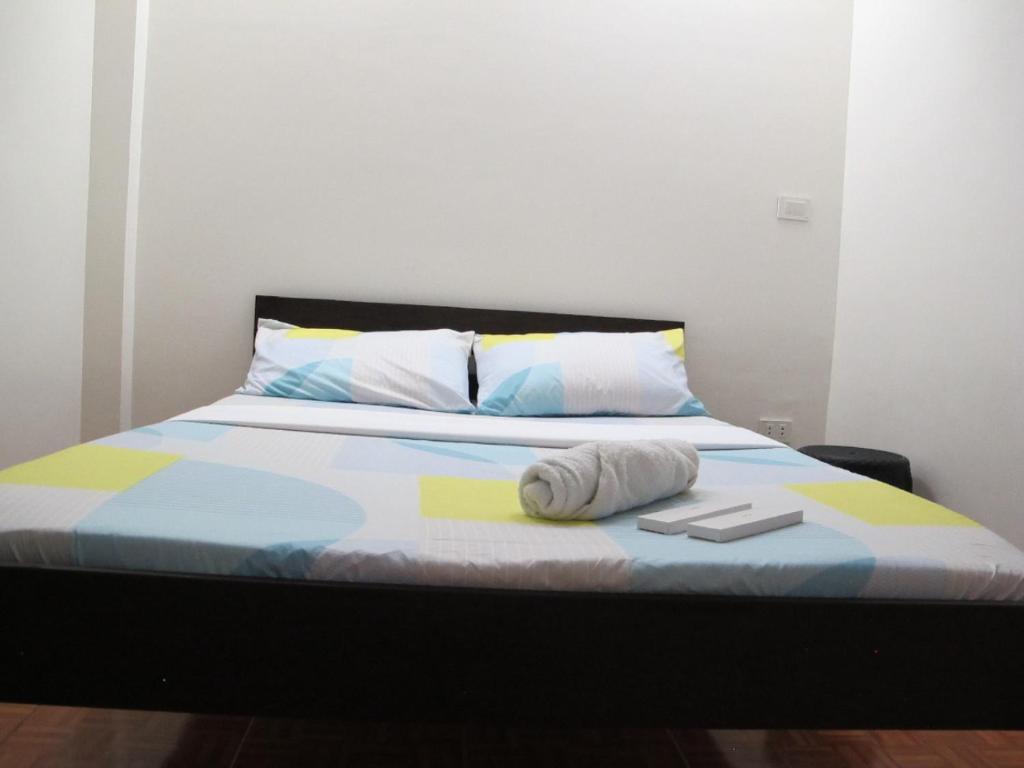 a bed with a towel and two books on it at Leo Green Apartelle in Jagna