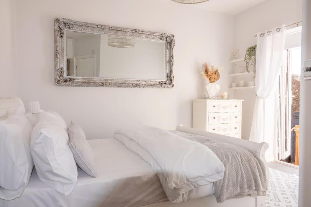 a white bedroom with a white bed and a mirror at The Seashells Whitstable in Kent