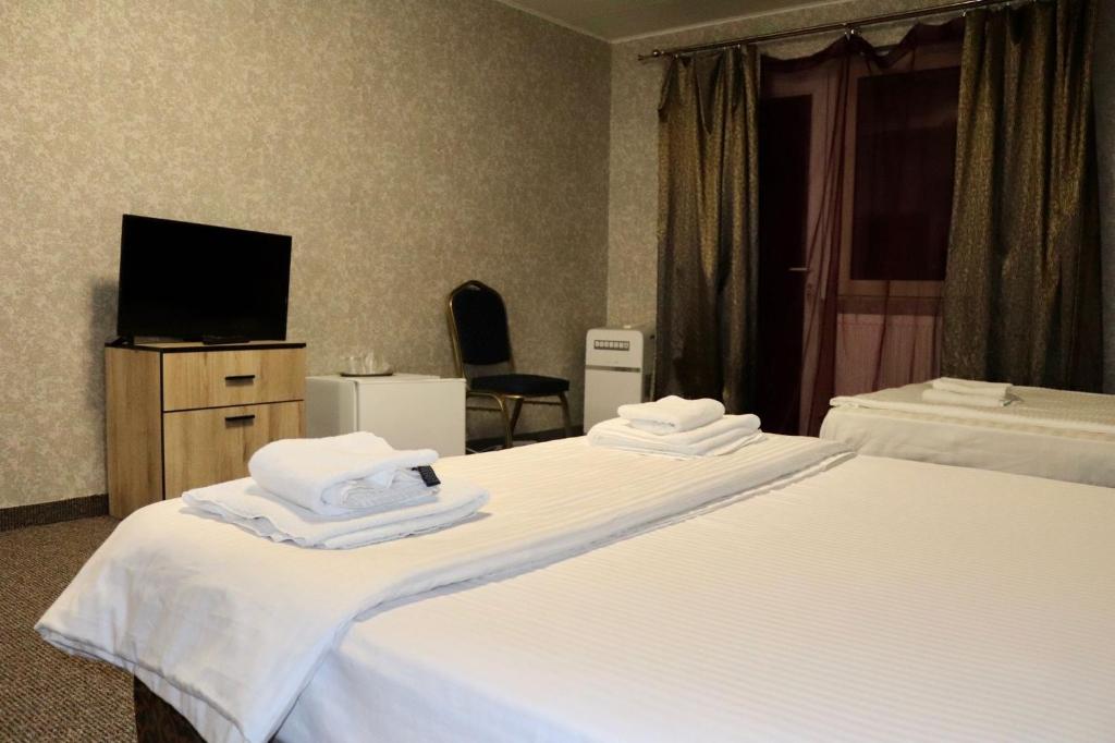 a hotel room with two beds and a flat screen tv at Complex Dalex in Drăgăşani