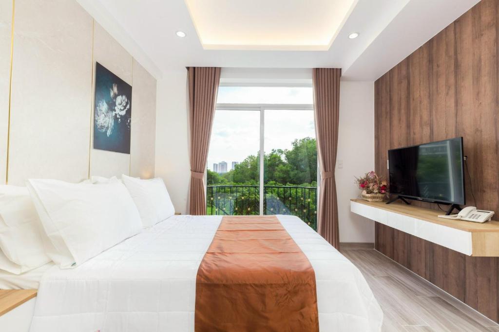 a bedroom with a bed and a tv and a balcony at NiNa APARTHOTEL in Ho Chi Minh City