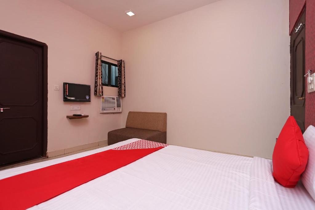 a bedroom with a bed and a chair and a mirror at Flagship Hotel Gurukripa in Raipur