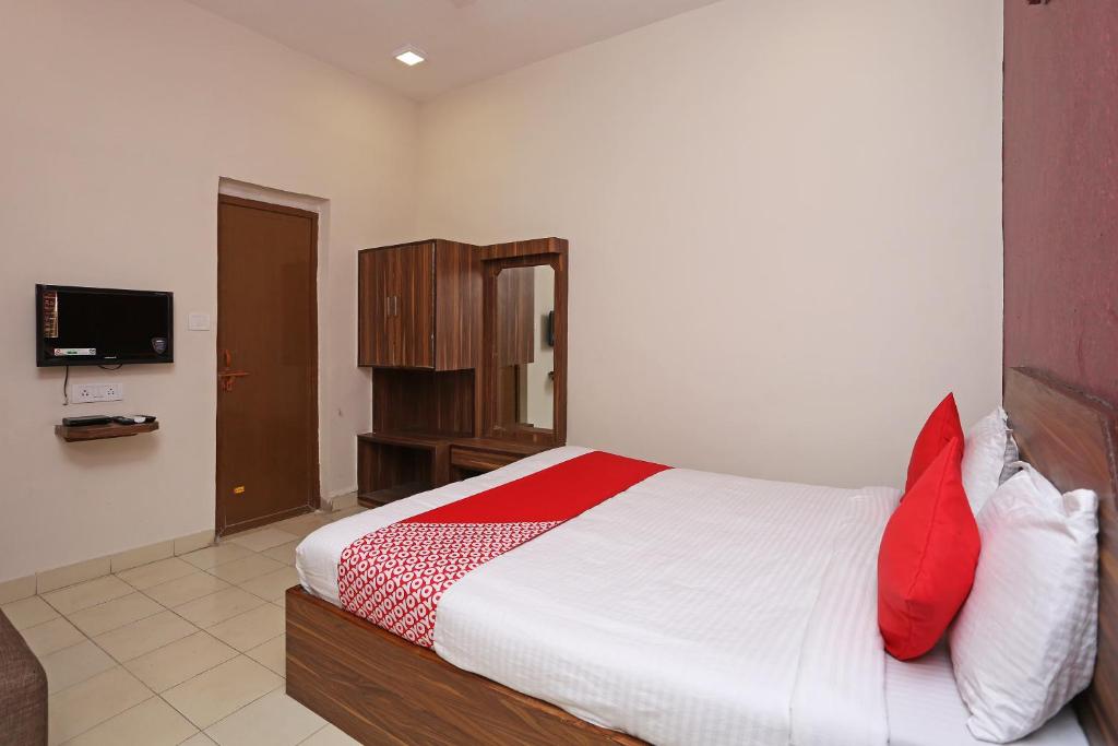 a bedroom with a bed with red pillows and a television at Flagship Hotel Gurukripa in Raipur