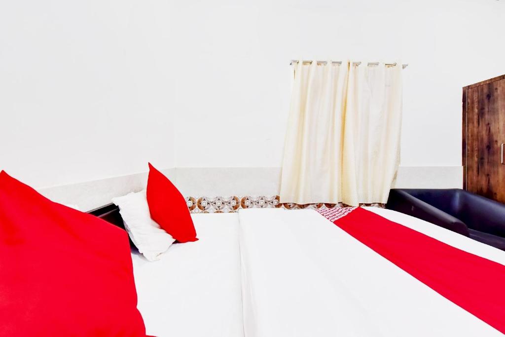 a bedroom with red and white pillows and a couch at OYO Hotel Paradise Inn in Jodhpur